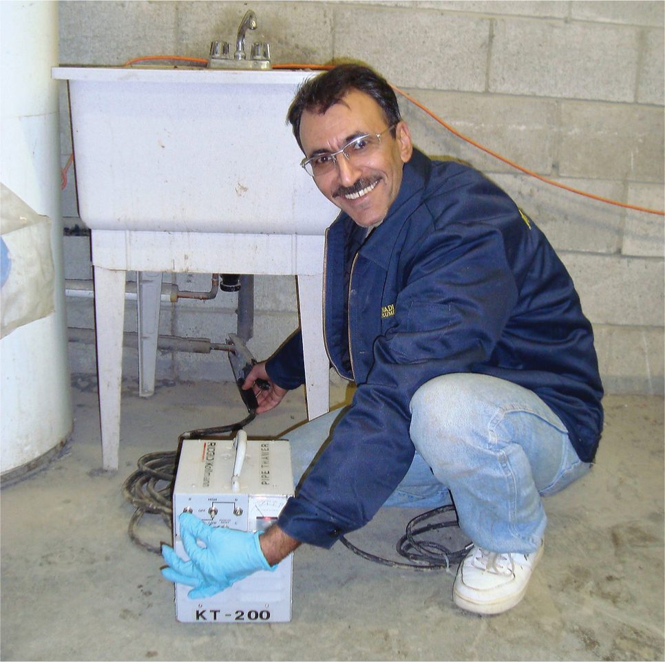 Plumber inspecting outdoor faucet in Toronto during summer maintenance.